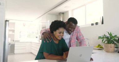 Çeşitli çiftler, evlerinde, modern mutfakta dizüstü bilgisayarda heyecanlı bir şekilde görüntülü sohbet ediyorlar. Teknoloji, iletişim, çeşitlilik, ev, yaşam tarzı, online