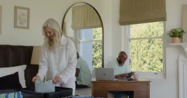 Üst düzey çift yeşil evrakları inceledikten sonra çantalarını yataklarına yerleştiriyor ve giysilerini katlıyorlar. Seyahat, organizasyon, işbirliği, yaşam tarzı, yerli, samimi, minimalist