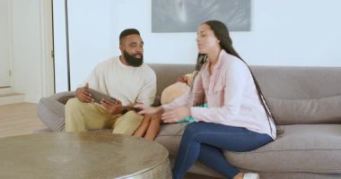 Çeşitli aileler, rahat oturma odasında tablet ve oyuncak ayıyla kardeş sürprizi duyuruyor. Aile, duyuru, sevinç, birliktelik, rahatlık, teknoloji, bağlılık