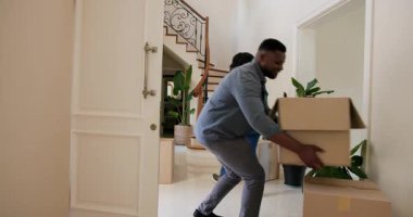 Mutlu siyah kadın ve erkek, karton kutuları ön kapıdan taşıyıp güneşli bir günde yeni bir eve taşınıyorlar. Yeni ev, mülk, mutluluk, yaşam tarzı ve ilişki kavramı.