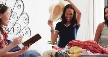 Çeşitli bayan arkadaşlar bavullarını bavula koyup hasır şapka ve pembe bikini deniyorlar. Seyahat, arkadaşlık, toplanma, moda, eğlence, yaşam tarzı, açık hava.