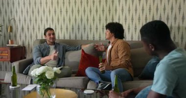 Oturma odasındaki kanepeye yerleşip bira içerken not defterine yazılan yazıyı yudumlayan farklı arkadaşlar. Gündelik, sosyalleşme, sohbet, rahatlama, iç mekan, dostluk, arkadaşlık.