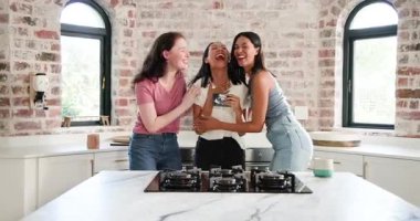 Mutfaktaki mermer adada elinde kamera ve kart olan çeşitli bayan arkadaşlar neşeyi paylaşıyor. Arkadaşlık, kutlama, birliktelik, samimi, rahat, neşe, aile içi