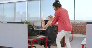 Çeşitli iş arkadaşları eğlenceyi kutlarken aynı zamanda sandalyeyi açık ofis alanında şakacı bir şekilde itiyorlar. Kutlama, takım çalışması, işbirliği, mutluluk, ofis, oyuncu, arkadaşlık