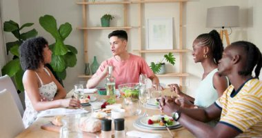 Çeşitli arkadaşlar kadehleri kaldırıyor ve yemek masasının etrafında yemek ve dekoratif bitkilerle sohbet ediyorlar. Kutlama, toplanma, arkadaşlar, yemek, yemek, sohbet, misafirperverlik
