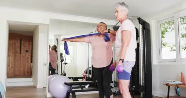 Kıdemli arkadaşlar spor salonunda mavi direniş bandıyla çalışıyorlar. fitness, egzersiz, arkadaşlık, güçlendirme, esneklik, ev, aktif