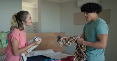 Genç çift yatak odasında bavullarını topluyor, birlikte tatile hazırlanıyorlar, evde. Seyahat, ilişki, eğlence, bavul, seyahat, hazırlık.