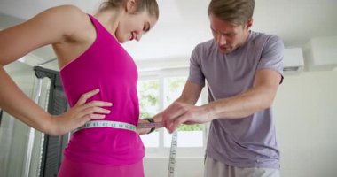 Vücut geliştirme hedeflerine odaklanmış, kemeri evde bantla ölçen bir çift. egzersiz, motivasyon, refah, ölçüm, sağlık, yaşam tarzı
