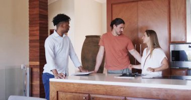 Mutfaktaki arkadaşlar tablet kullanırken ve gülümserken planları tartışıyorlar. Arkadaşlık, toplanma, teknoloji, iletişim, yaşam tarzı, sohbet