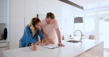 Modern mutfakta belgeleri birlikte inceleyen mutlu bir çift. Geleceği planlıyorlar. Evde. danışmanlık, yaşam tarzı, ilişki