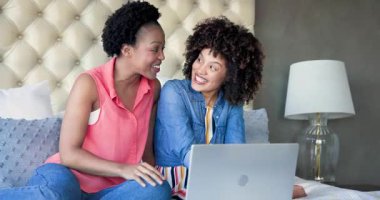 Evde dizüstü bilgisayar kullanırken birlikte gülen iki kadın, kaliteli zaman geçirmenin keyfini çıkarıyorlar. Teknoloji, arkadaşlık, yaşam tarzı, bağlanma, rahatlama, rahatlama.