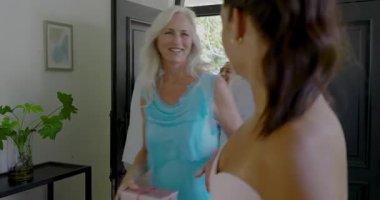 Kapısı açık Asyalı bir adam, evde toplanması için yeşil şişe uzatan dostları selamlıyor. Konukseverlik, kutlama, zarafet, neşe, iç mekan, sosyalleşme, modern