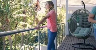 Genç çift balkonda güneşli bir günün tadını çıkarıyor. Rahatlıyor ve manzaranın tadını çıkarıyor. Rahatlama, rahatlama, dinginlik, güneş ışığı, birliktelik, açık hava.