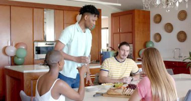 Arkadaşlar evde birlikte yemek yiyor, akıllı telefonlarıyla anları yakalıyorlar. Arkadaşlık, yemek, toplanma, kutlama, teknoloji, mutluluk.