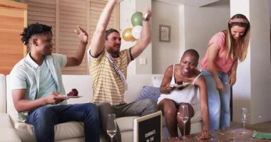 Arkadaşlar evde kutlama yapıyor, neşeli ifadelerle pasta ve konfeti yiyorlar. Kutlama, parti, mutluluk, arkadaşlık, yemek, tatlı