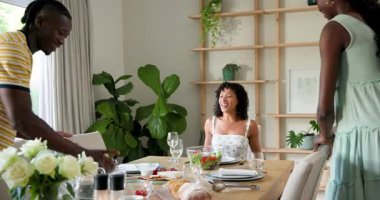 Çeşitli arkadaşlar yemek odasındaki ahşap masanın etrafında sohbet ediyorlar, salata kasesi ve somun ekmeği paylaşıyorlar. Yemek, toplanma, sohbet, sıcaklık, keyif, konukseverlik, aşçılık