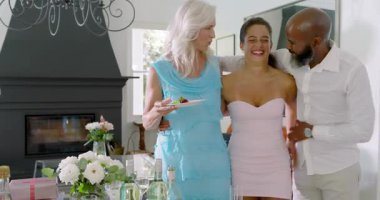 Çeşitli aile üyeleri ve arkadaşlar oturma odasına girince sarılıyor, gülüyor ve masanın yanında şarap kızartıyorlar. Kutlama, toplanma, samimiyet, arkadaşlık, zarafet, sıcaklık, neşe