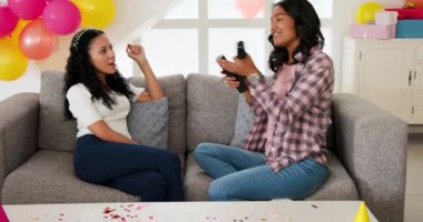 Çeşitli kız kardeşler oturma odasında balonlar ve konfetilerle kutlama yapıyorlar. Parti, şenlikli, neşeli, neşeli, aile, bağ, modern