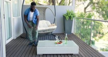 Afro-Amerikalı çift terasa giriyor yastıklar ve şarap aperatifleri düzenliyor kadınları hazırlıyor. Romantik, açık hava, rahat yaşam tarzı, boş zaman, atmosfer, zarafet