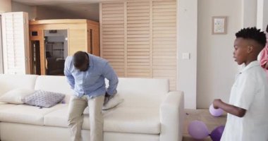 Baba ve oğul evdeki kanepede şakacı bir şekilde dinleniyorlar ve etrafta balonlar var. Aile, bağlılık, ebeveynlik, birliktelik, boş zaman, kutlama