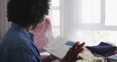 Afro-Amerikalı ve Asyalı arkadaşlar açık bavul ve kontrol listesiyle kızlar için toplanıyorlar. Seyahat, organizasyon, arkadaşlık, planlama, macera, eğlence, takım çalışması