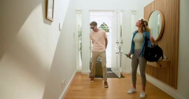 Çift eve bavullarıyla geliyor, gülümsüyor ve parlak koridorda sohbet ediyorlar. Seyahat, bagaj, varış, sohbet, eve dönüş, mutluluk