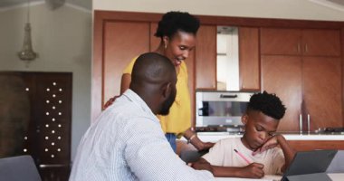 Aile evde güzel vakit geçiriyor, çocuk çizimi yapıyor ebeveynler de mutlu bir şekilde izliyor. bağlanma, birliktelik, yaratıcılık, mutluluk, ebeveynlik, eğlence