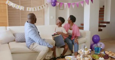 Baba, oğlana doğum günü kutlaması sırasında ailesiyle birlikte evde hediye veriyor. Mutluluk, babalık, bağlılık, neşe, ebeveynlik, neşe