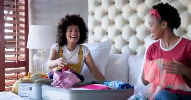 Bavul hazırlıyor, çeşitli kadın çiftler yatakta tatile hazırlanıyor, evde birlikte gülümsüyorlar. Seyahat, arkadaşlık, bagaj, hazırlık, turizm, kaynaşma