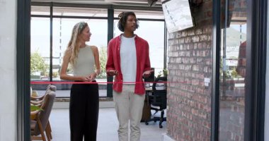 Çeşitli iş arkadaşları modern ofiste kurdele kesiyor, kırmızı kurdele tutuyor ve heyecan gösteriyorlar. Tören, takım çalışması, başarı, kutlama, işbirliği, modern, ofis