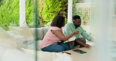 Verandada dinlenen Afro-Amerikan çift tablet kullanıyor ve sohbet ediyorlar. Teknoloji, iletişim, yaşam tarzı, rahatlık, rahatlama, dijital