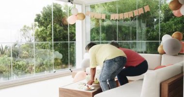 60. yaş gününü evde pasta tutarak kutlayan kıdemli bayan arkadaşlar. Kutlama, mutluluk, arkadaşlık, balonlar, doğum günü, canlı, neşeli