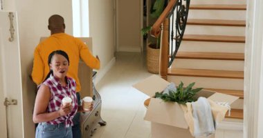 Mutlu siyah kadın ve erkek, karton kutuları ön kapıdan taşıyıp güneşli bir günde yeni bir eve taşınıyorlar. Yeni ev, mülk, mutluluk, yaşam tarzı ve ilişki kavramı.