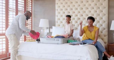 Aile bavullarını yataklarına koyuyor, evde heyecanlı ve neşeyle tatile hazırlanıyor. Seyahat, bagaj, aile zamanı, planlama, mutluluk, tatil