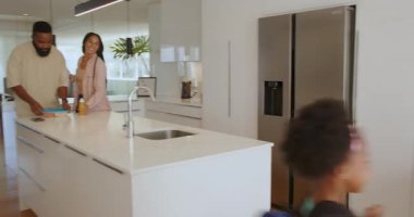 Çeşitli aileler, kızlarını mavi sırt çantası ve şişe kullanarak modern mutfakta okula hazırlıyorlar. Aile, hazırlık, eğitim, takım çalışması, rahat, ebeveynlik, modern, etkileşim, yaşam tarzı