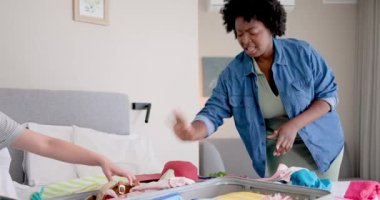 Çeşitli arkadaşlar modern yatak odasındaki kızlar gezisi için renkli kıyafetler ve seyahat takımları hazırlıyorlar. Paketleme, arkadaşlık, macera, canlı, modern, işbirliği, seyahat