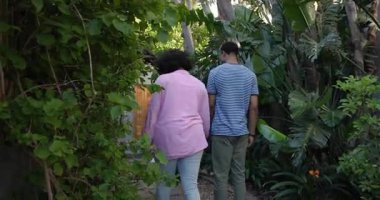 Yeşilliklerle çevrili, yemyeşil bahçede romantik anın tadını çıkaran genç bir çift. Romantizm, aşk, doğa, sevgi, bahçede, samimiyet