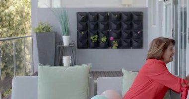 Kıdemli çift aperatifleri getirmeden ve şarap kadehleriyle kadeh kaldırmadan önce balkon kanepesinde sohbet ediyorlar. Açık hava salonu, iletişim, rahatlık, zarafet, kutlama, uyum, yaşam tarzı.