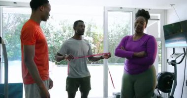 Afrika kökenli Amerikalı bir çift spor salonunda antrenörle bel ölçüşüyor, motive oluyorlar. Fitness, egzersiz, kişisel antrenör, sağlık, motivasyon, sağlık