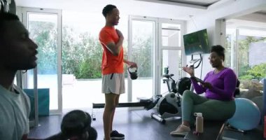 Afrika kökenli Amerikalı çift evde spor yapıyor, kettlebell ve tablet kullanıyorlar. Spor, spor, egzersiz, teknoloji, eğitim, yaşam tarzı
