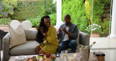 Afro-Amerikalı çift terasta yeşillik ve aperatiflerle sohbet ediyor. Rahatlama, yaşam tarzı, birliktelik, bağ.