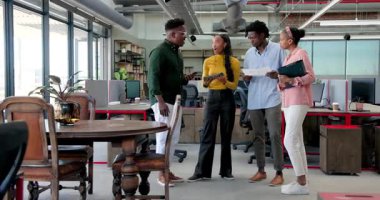 Afrika kökenli Amerikalı meslektaşlar, bilgisayar ve klasör kullanarak modern ofisteki ekip üyelerini tebrik ediyor. Takım çalışması, işbirliği, başarı, modern, ofis, masa, profesyonel