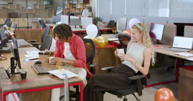 Modern ofiste birbirlerini tebrik eden çeşitli iş arkadaşları hediye kutusunu, kupayı ve balonları paylaşıyorlar. Kutlama, takım çalışması, yoldaşlık, başarı, hediyeler, başarı, gelişigüzel