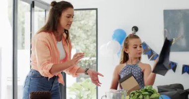 Anne ve kızı hediye paketi alıyor, altın hediye kutusunu açıyor, evde parti için atıştırmalıklar hazırlıyor. Aile, kutlama, neşe, birliktelik, şenlik, gülümseme, bağ