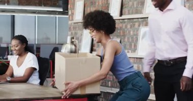 Çeşitli iş arkadaşları modern ofisteki iniş kontratını karton kutu ve gülümsemeyle kutluyorlar. Kutlama, takım çalışması, heyecan, çağdaş, ofis, işbirliği, başarı