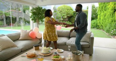 Kutlama sırasında evde kek ve balonlarla dans eden çift. Parti, mutluluk, yaşam tarzı, neşeli, yıldönümü, şenlikli