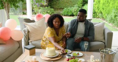 Pasta ve meyve tabağıyla kutlayan Afro-Amerikan çift terasta neşeli görünüyor. Kutlama, birliktelik, mutluluk, tatlı, toplanma, yemek