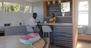 Afrika kökenli Amerikalı çift modern bar tezgahında şişe ve sırt çantasıyla etkileşim halindeler. Etkileşim, ev, bağ, yaşam tarzı, çağdaş, sıcaklık, arkadaşlık, gelişigüzel