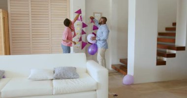 Balonlarla dekore edilmiş oturma odası, kutlama için gülümseyen Afro-Amerikan ailesi. Mutluluk, birliktelik, çok kültürlülük, çeşitlilik