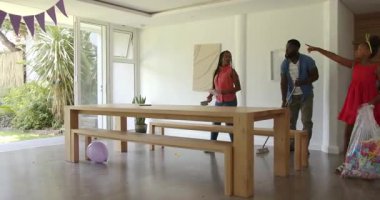 Afro-Amerikan üçlüsü, ahşap masa ve mor dekorla doğum günü eğlencesine katılıyor. Kutlama, doğum günü, parti, eğlence, etkinlik, dekorasyon, toplantı